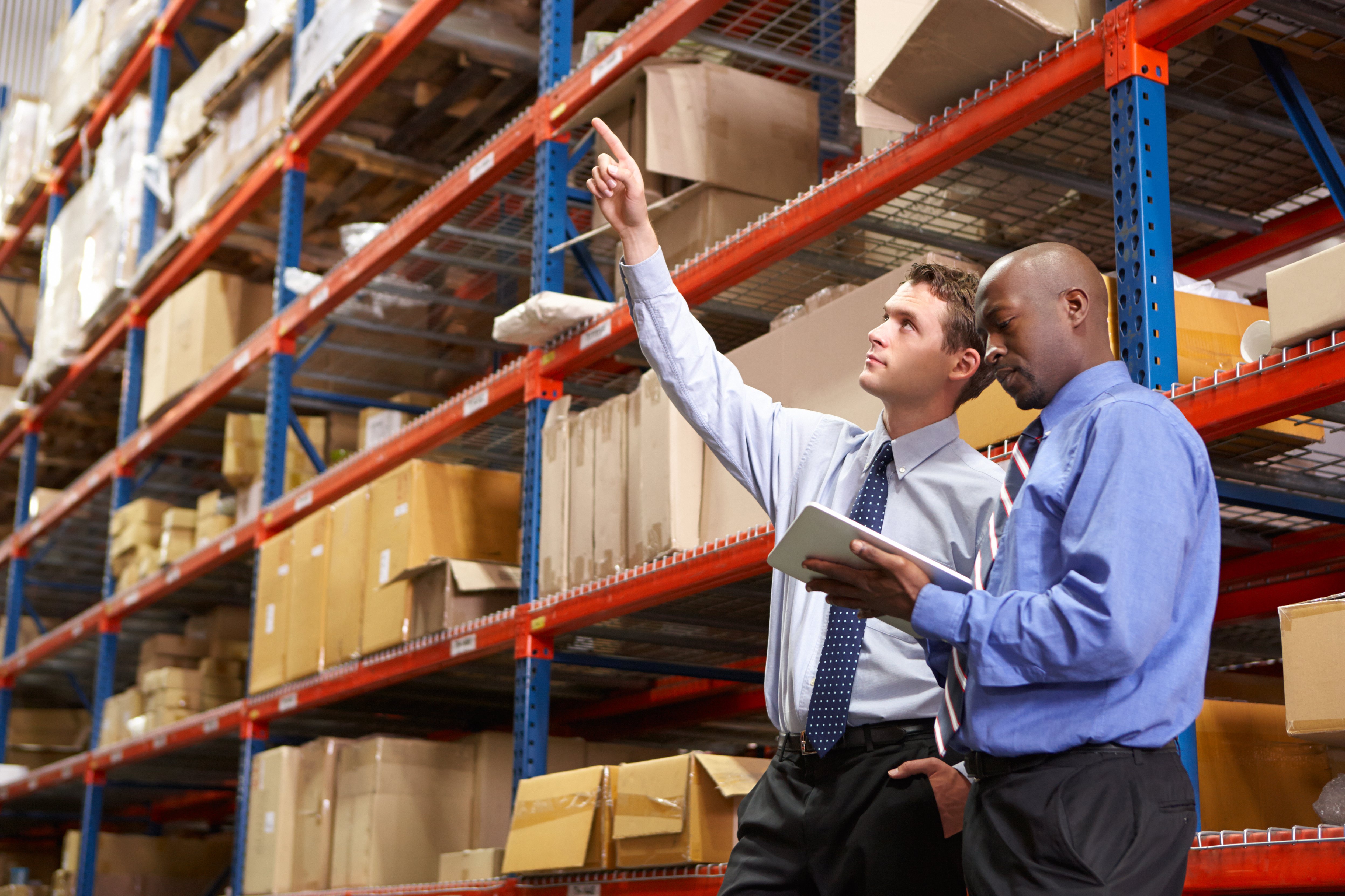 Supplier takes notes as his new client point to items in warehouse inventory