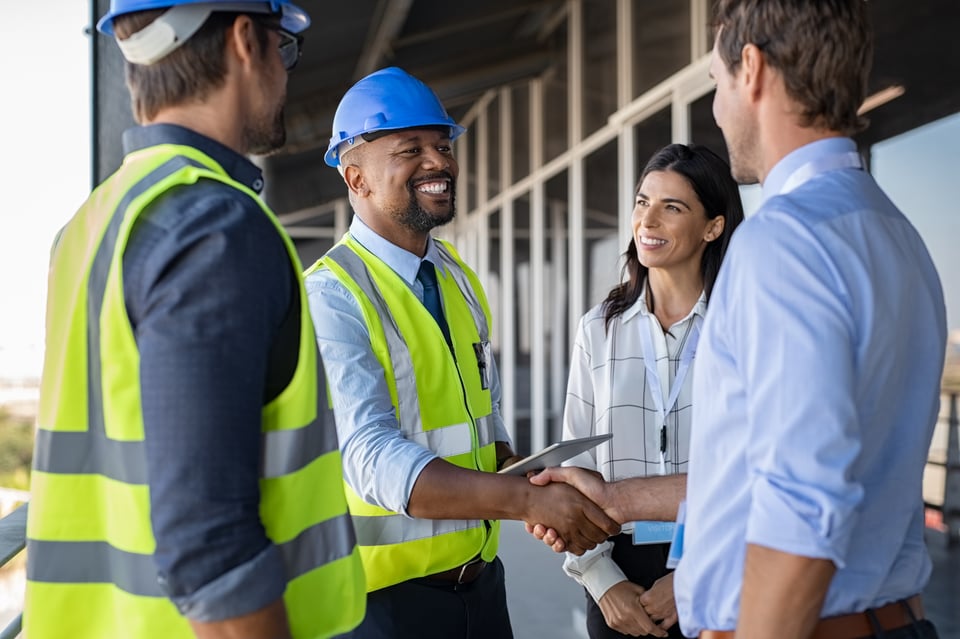 African American supplier shakes hands with corporate client after agreeing to do business with them.