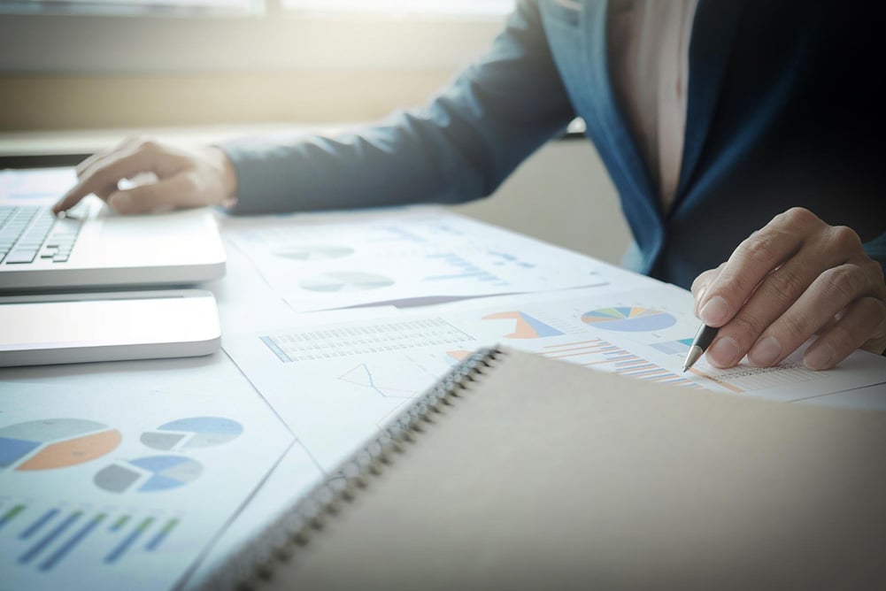 Business professional analyzing procurement data with charts and graphs on a desk, highlighting indirect spend management and cost optimization.
