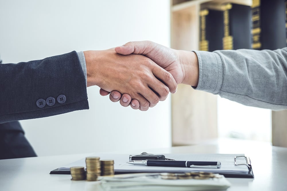 Business handshake symbolizing the impact of US-China tariff cuts on procurement, inflation control, and cost savings in global supply chains.